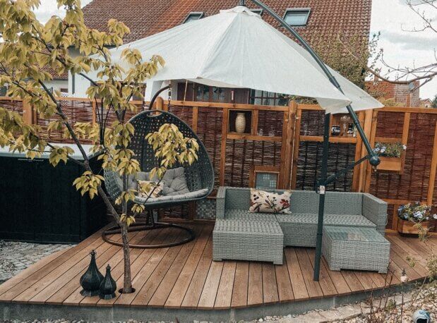 Holzterrasse mit Lounge-Möbeln und Sichtschutz