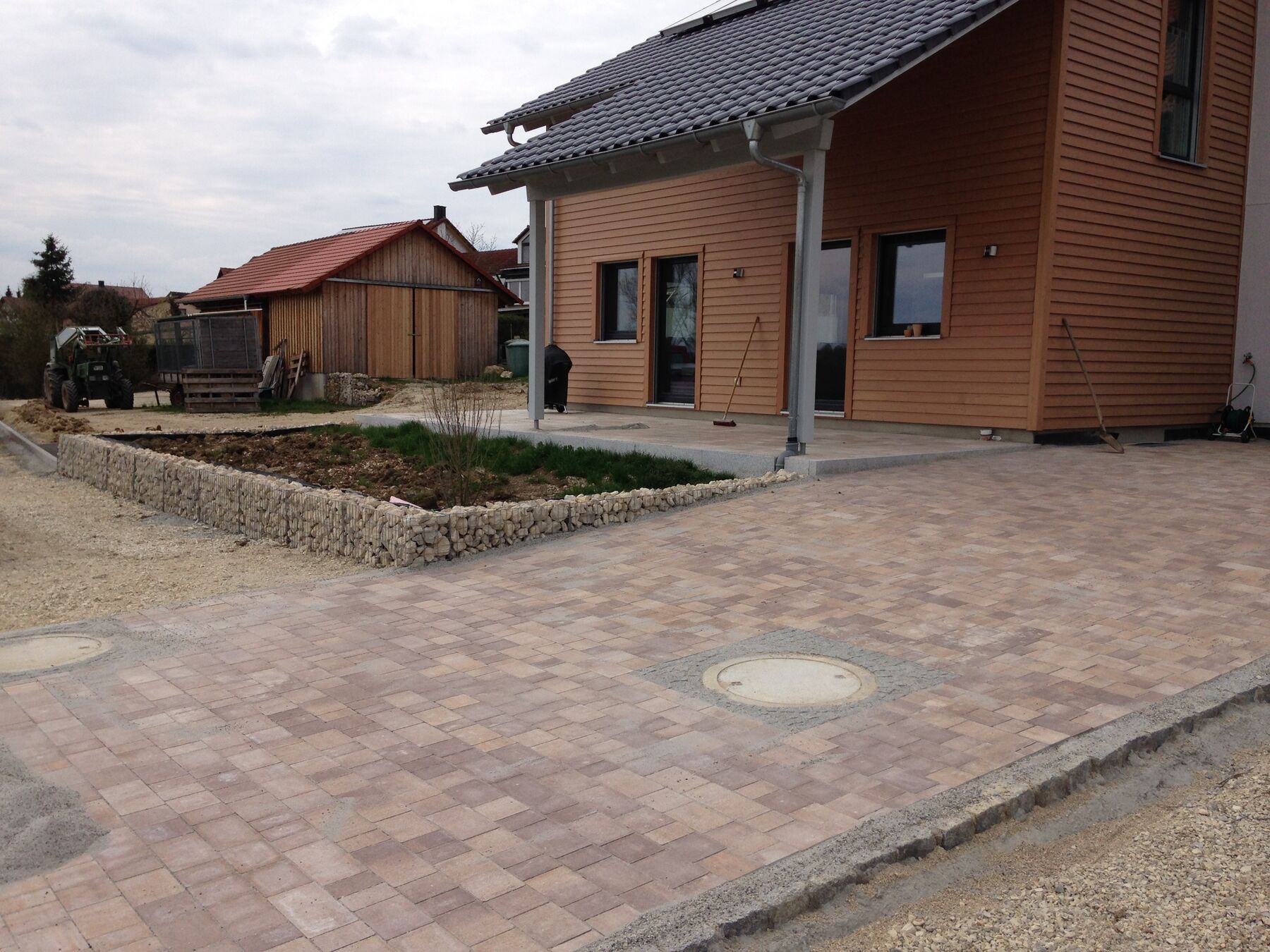 Neuanlage in Hienheim: Hofpflaster und Terrasse vor einem Haus mit Holzfassade